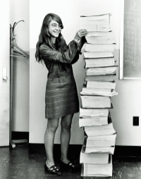 Margaret Hamilton stående vid en trave programkod, lika hög som hon själv.